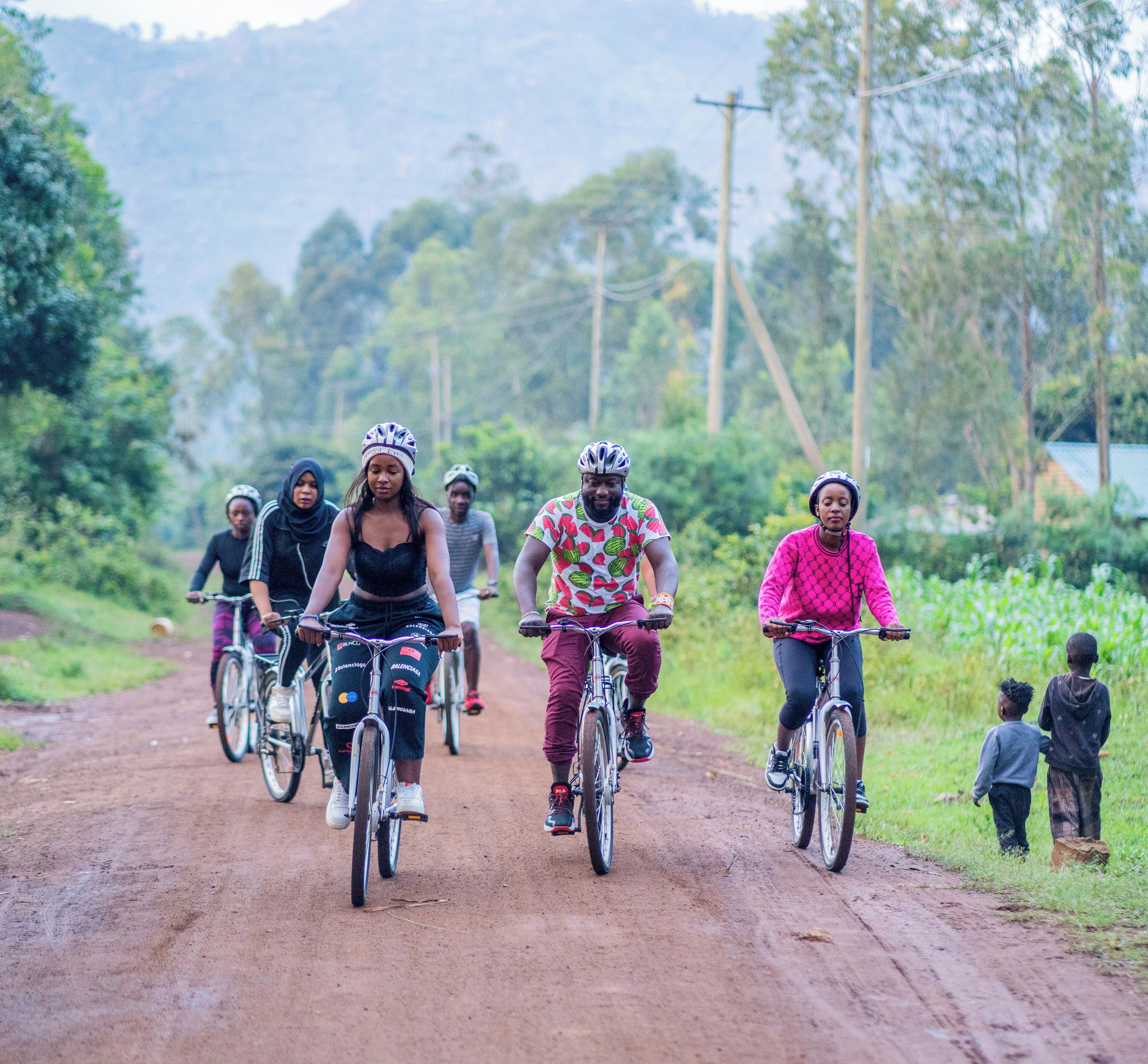 A group of people riding bicycles on a dirt road surrounded by greenery.