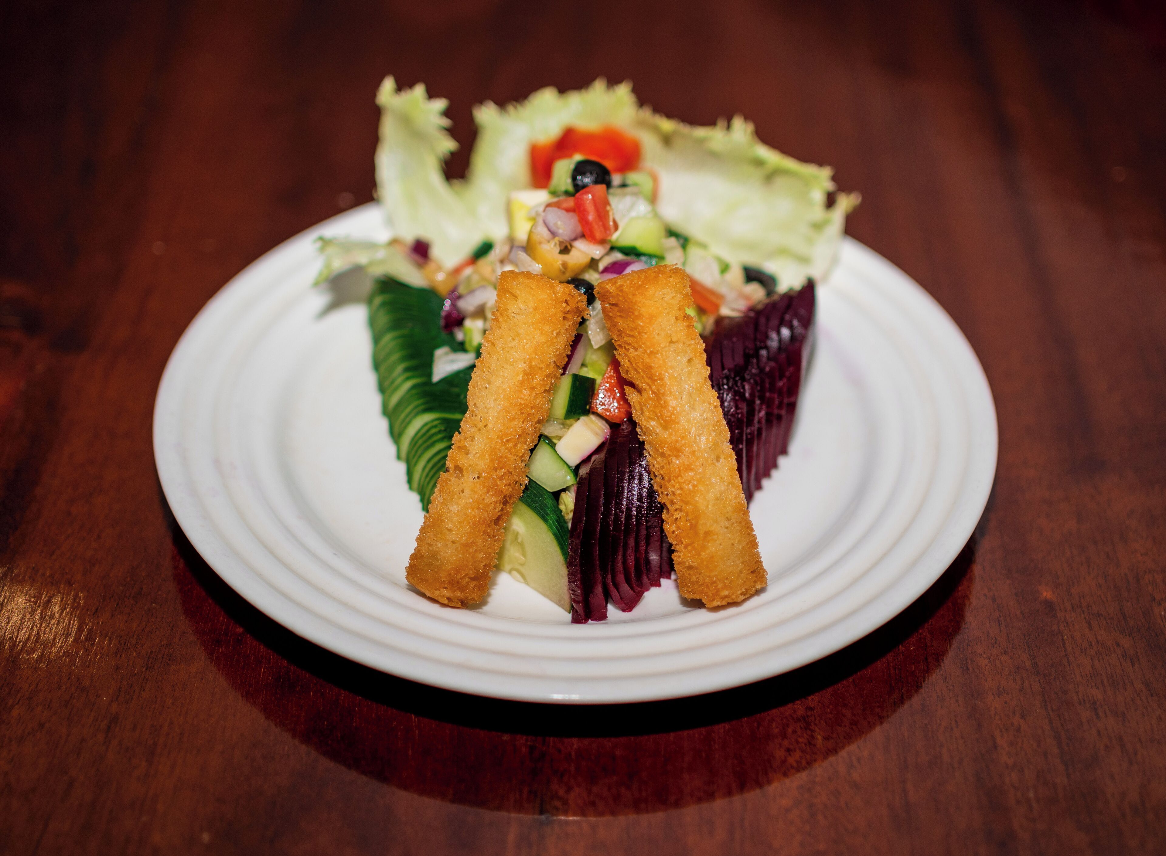 A plate of food with a salad and two breaded items on a white plate.