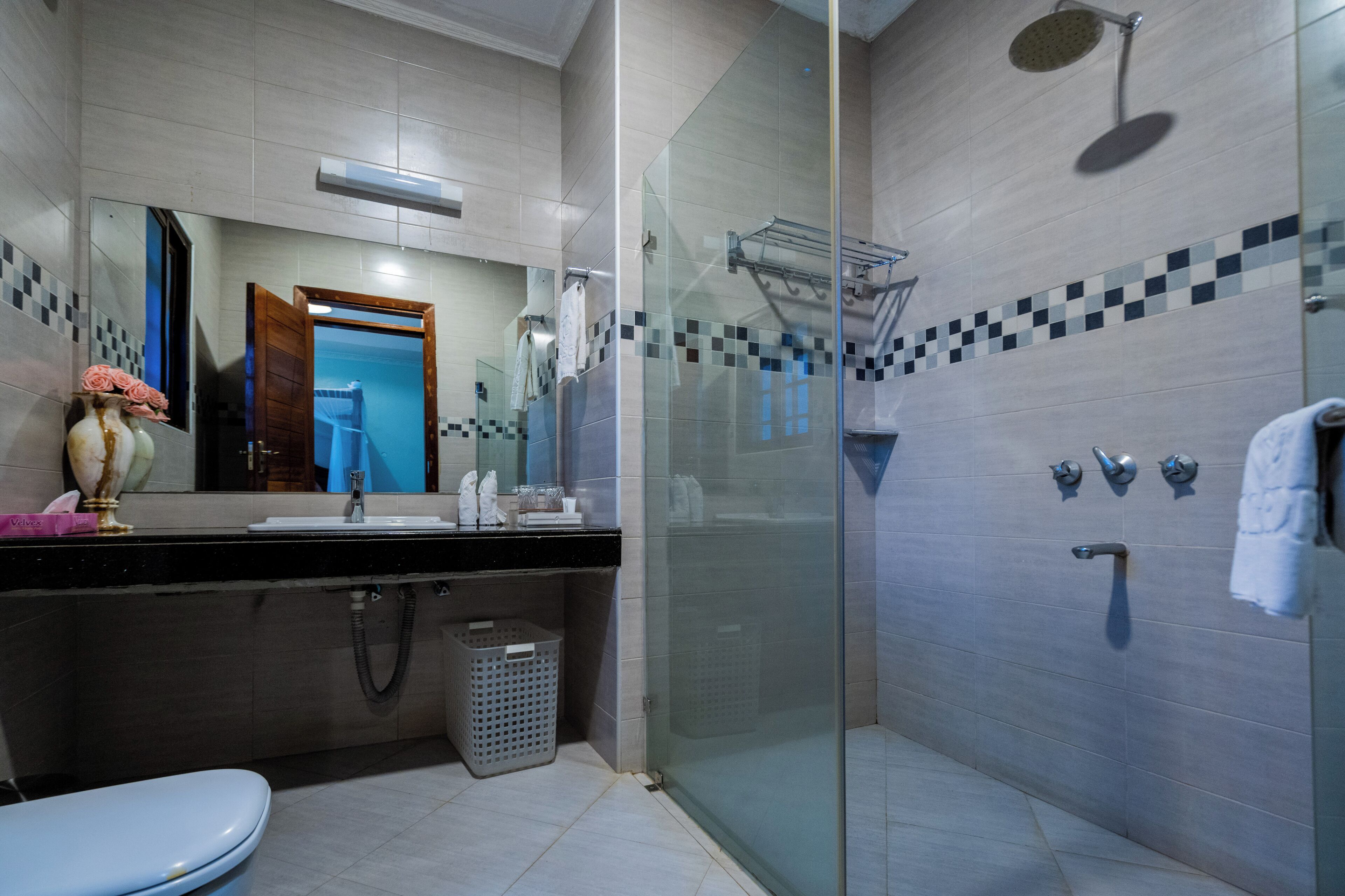 Une salle de bain moderne avec une douche à parois de verre, des toilettes, un lavabo et un miroir.