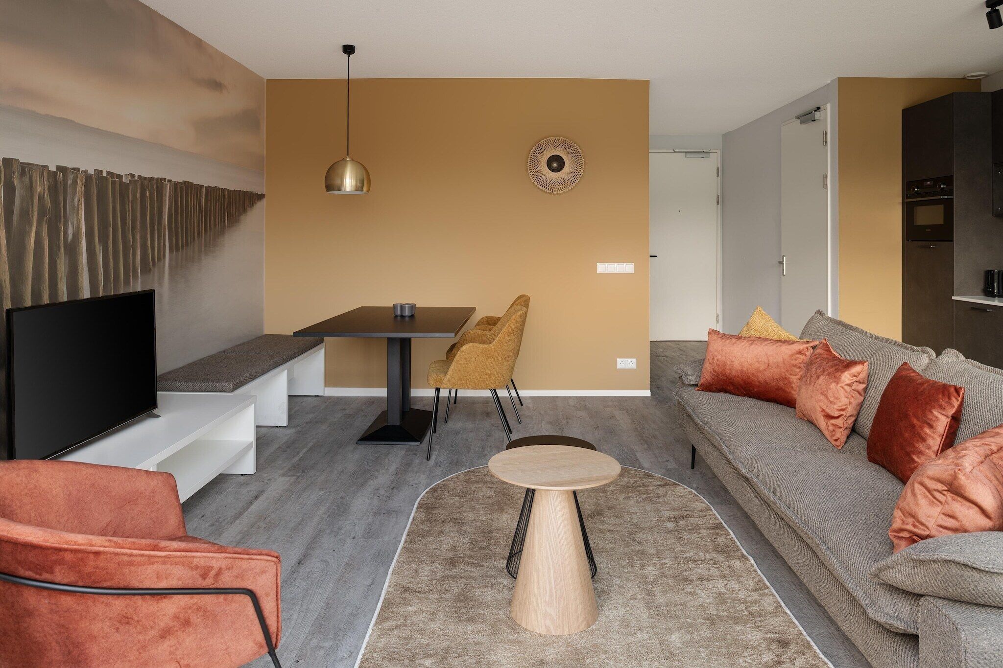 Een moderne woonkamer met een flatscreen televisie, een eettafel en een bank met kussens.