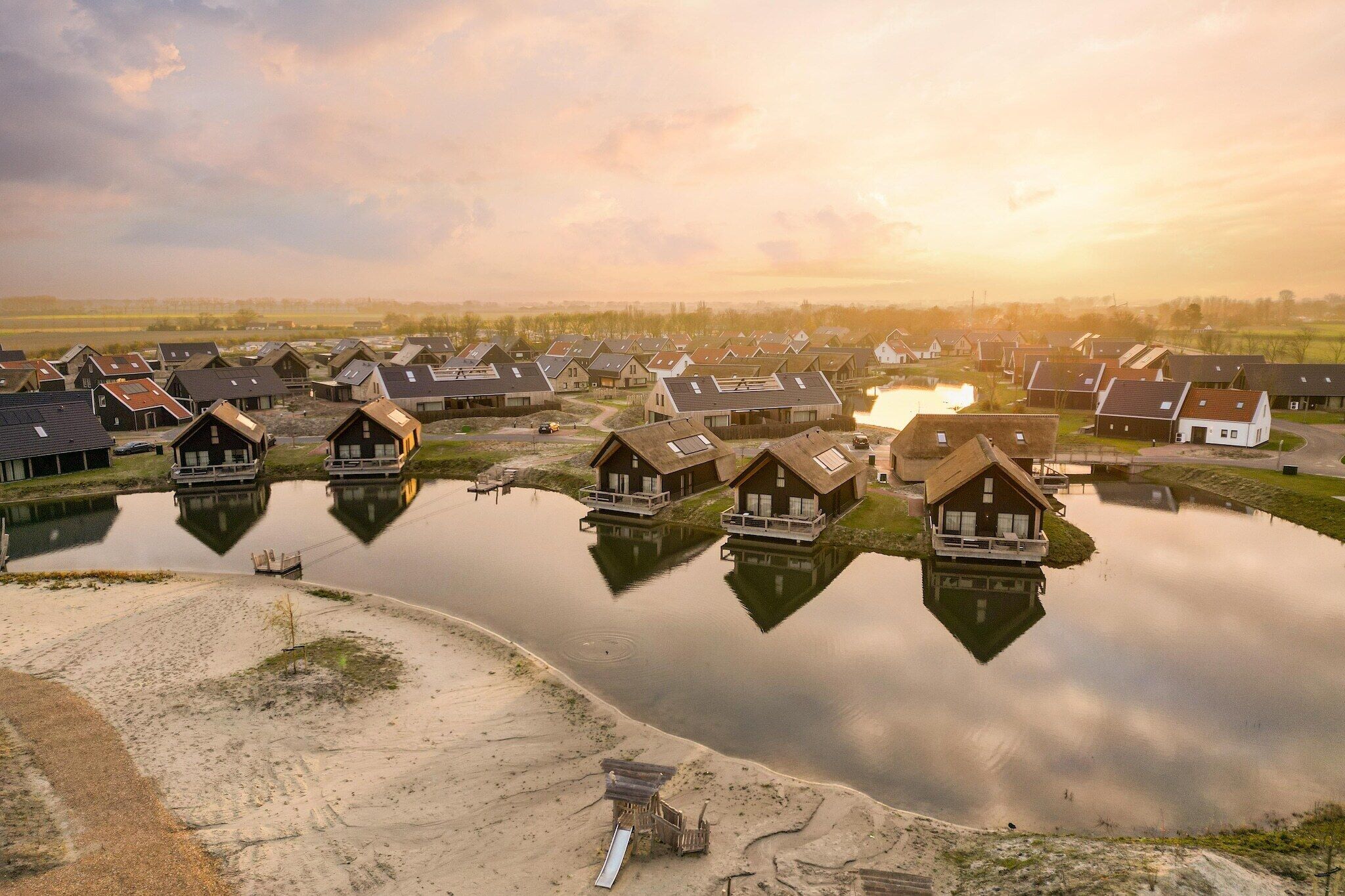 Un village au bord du lac, avec des maisons construites sur pilotis au-dessus de l’eau, qui présente un mélange d’architecture traditionnelle et moderne.