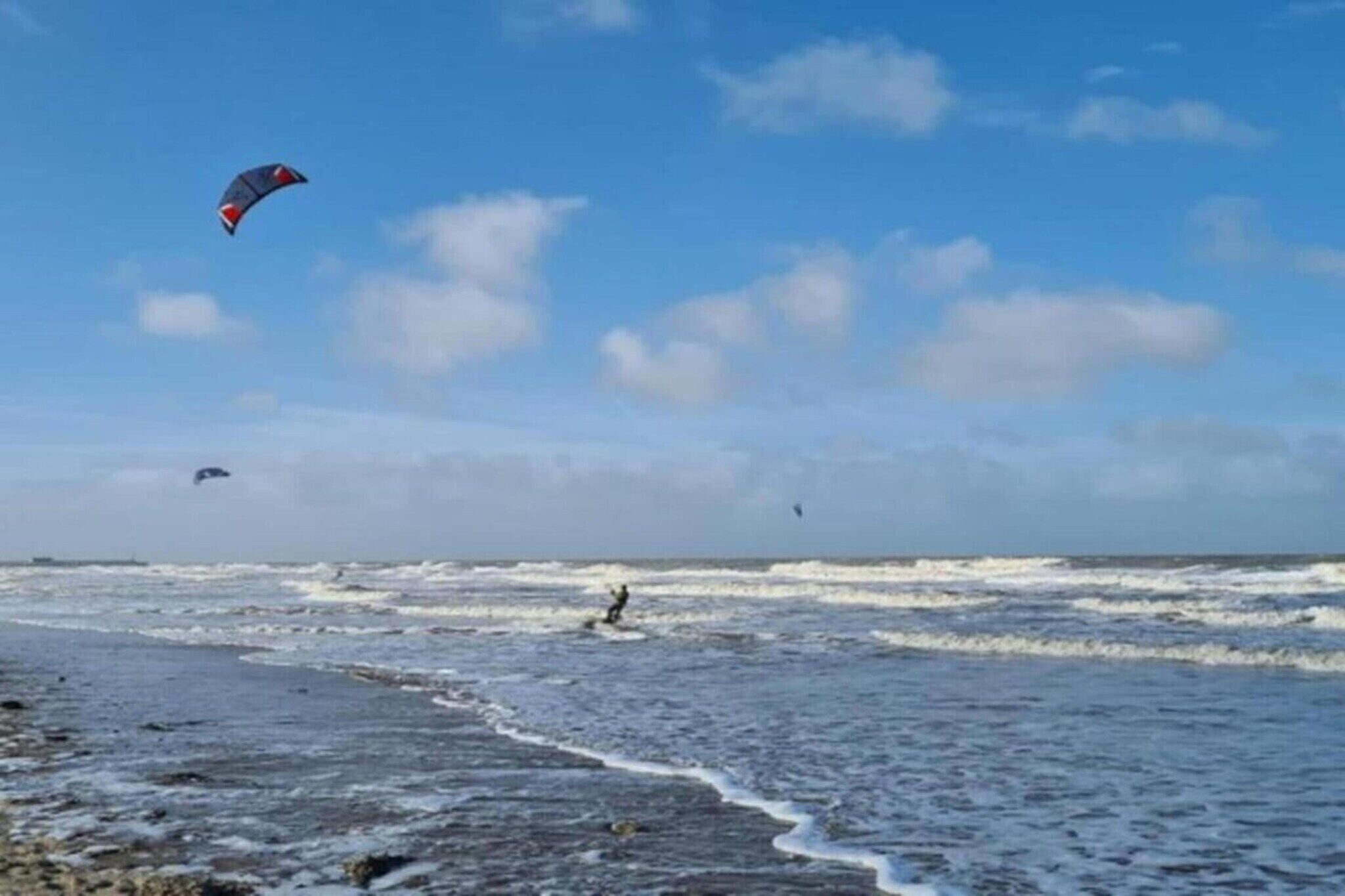 Una spiaggia con onde e una persona che fa surf.
