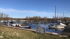 Ein Yachthafen mit verschiedenen Schiffen, einem Schild und wolkenlosem Himmel.