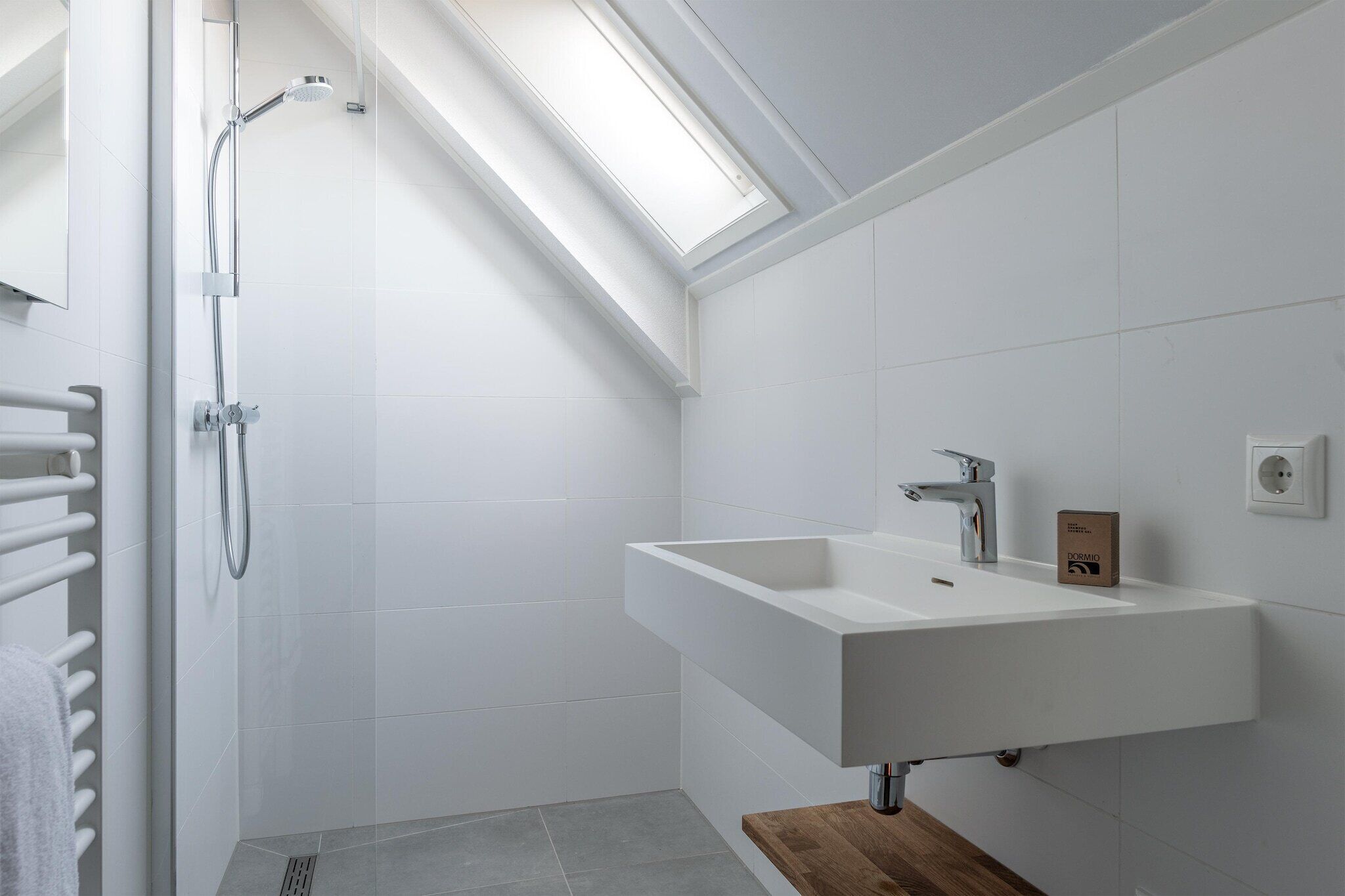A modern bathroom with a skylight, a freestanding sink, and a shower.
