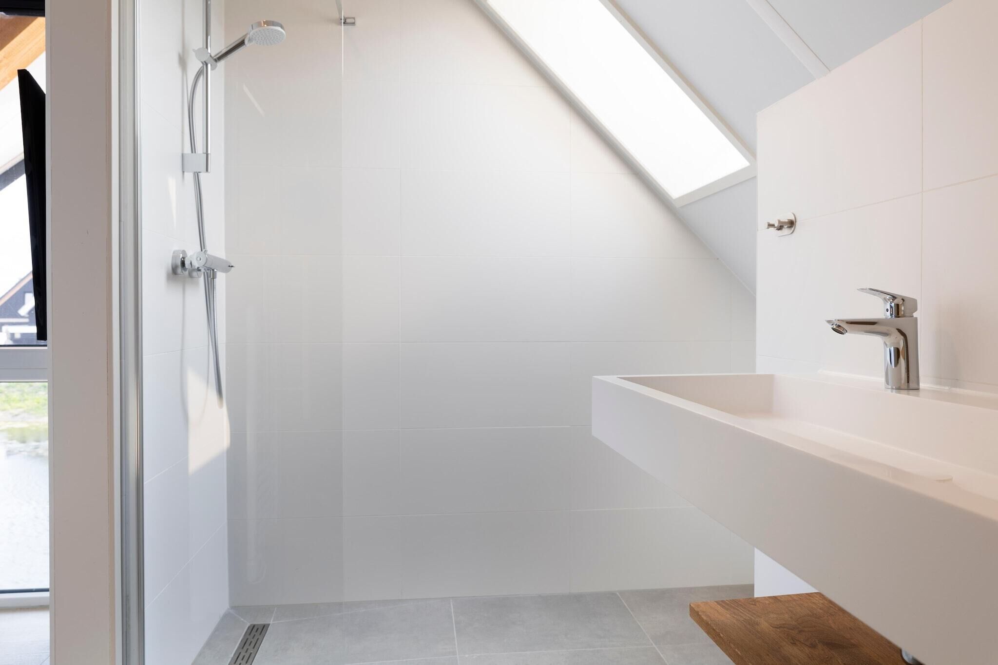 Un baño moderno con ducha, lavamanos y un banco de madera.