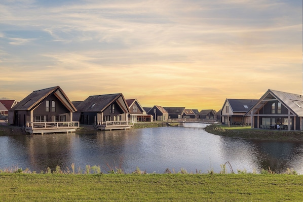 A row of modern houses with a water body in the foreground.