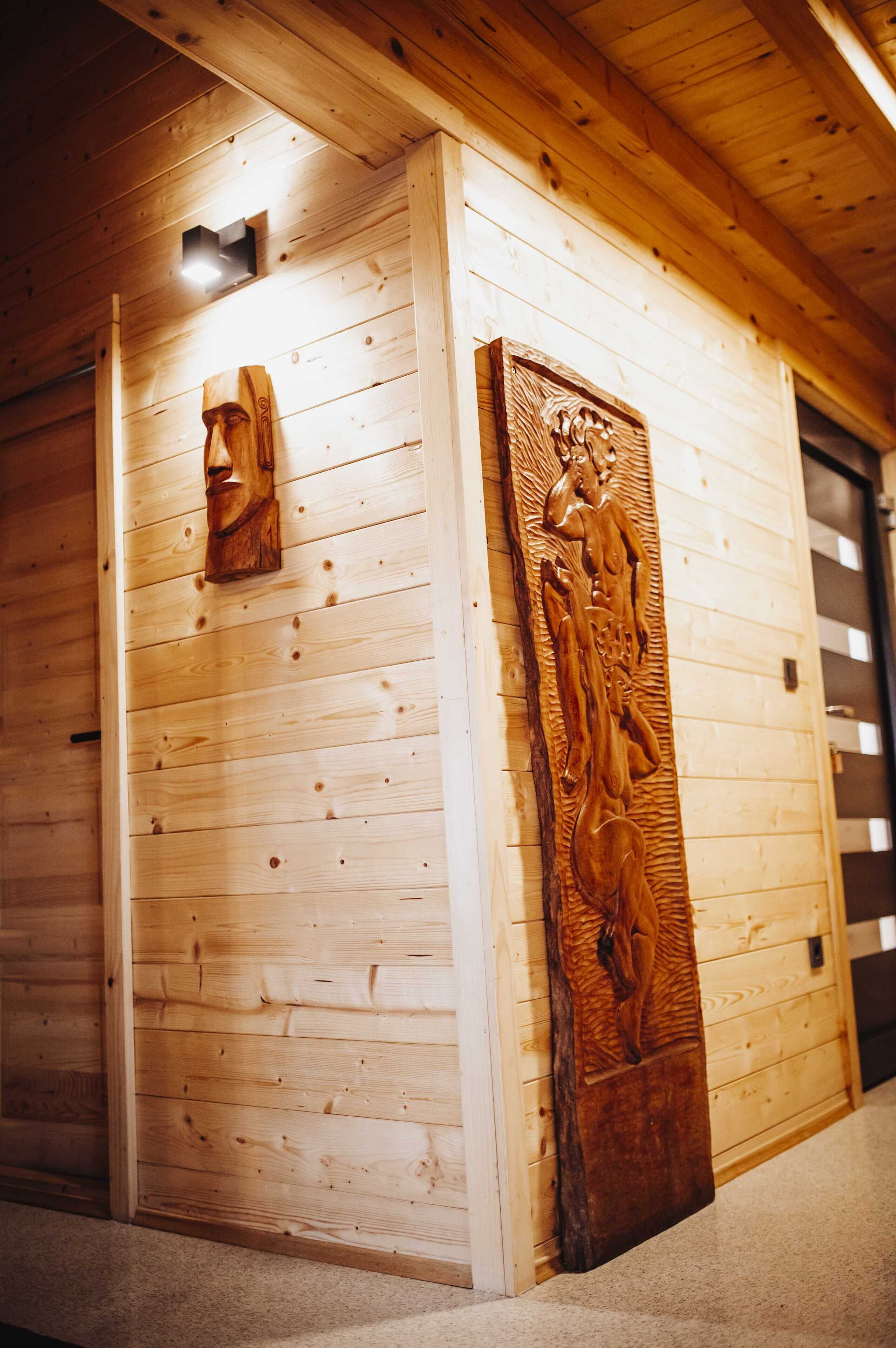 A wooden cabin interior with a carved wooden panel on the wall and a small light fixture above it.