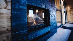 A stone fireplace with a glass front, set in a wooden wall.