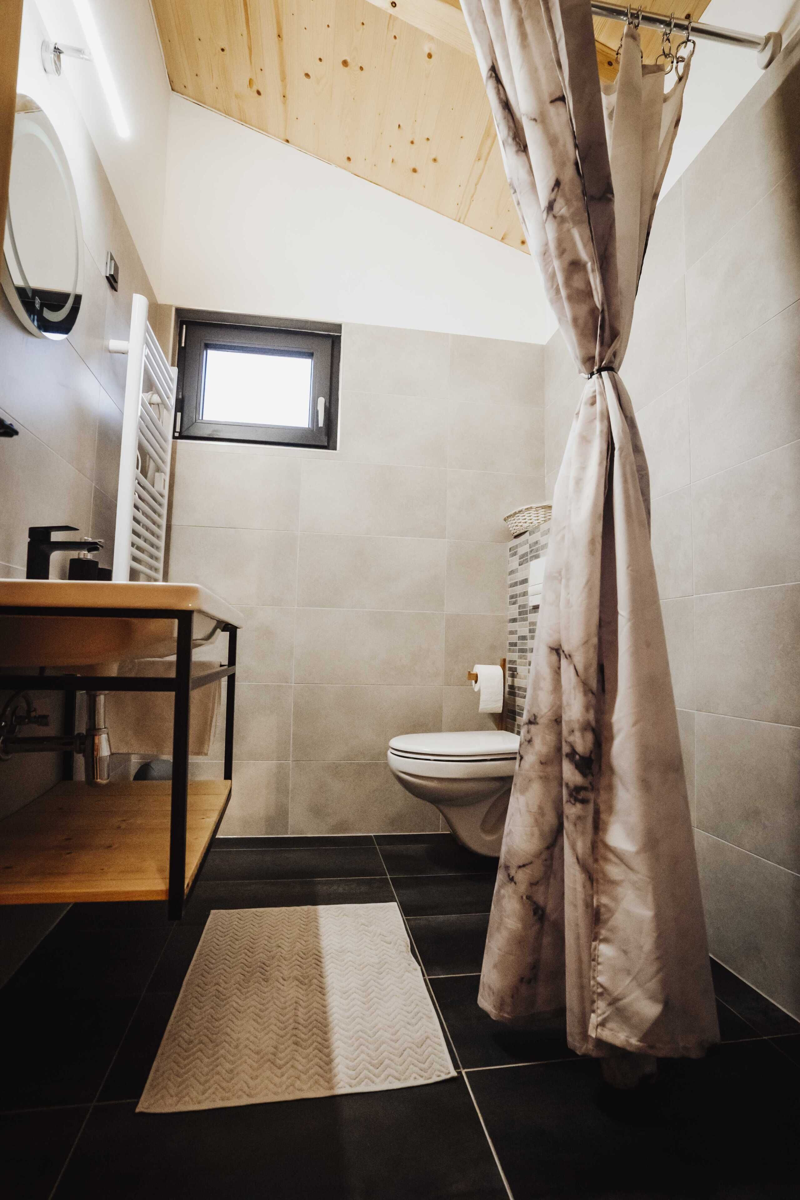 Ein Badezimmer mit Holzboden, Toilette, Waschbecken und Duschvorhang.