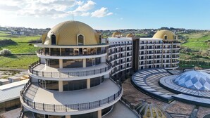Hotel com vários andares e design arquitetônico marcante, com uma cúpula central e várias varandas.