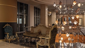 Um hall de entrada luxuoso com mobiliário requintado, um lustre imponente e piso de mármore.