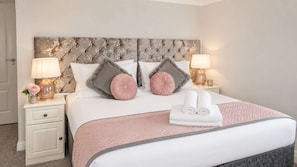 A neatly made bed with a pink and white color scheme, two bedside lamps, and a decorative headboard.