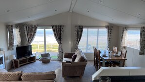 A spacious living room with a television, sofa, and dining area. - Beautiful Lodge w/Amazing Coastal Views (Hartlepool)
