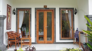 A covered porch with a wooden table and chairs, a glass door, and a small wooden bench. - Bali Menjangan Boutique Villas (Pemuteran)