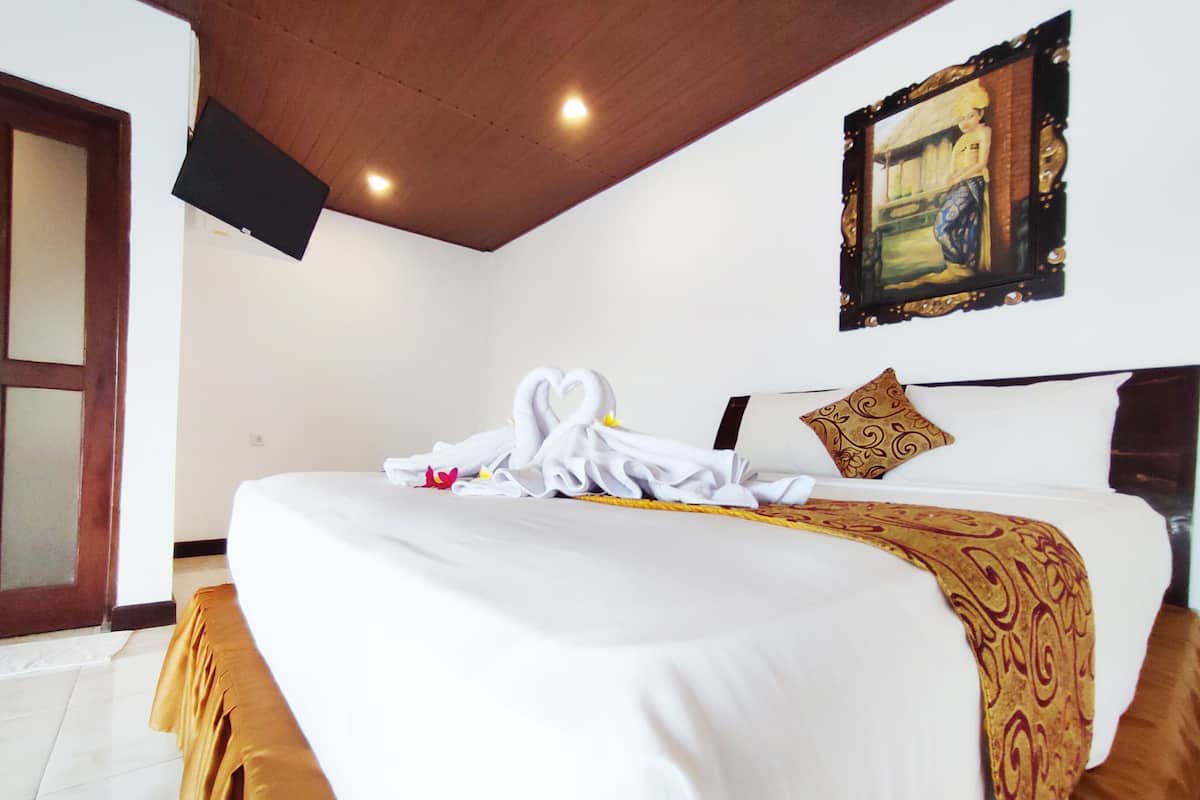 Una habitación de hotel con una cama, un cuadro en la pared y un televisor instalado en el techo.