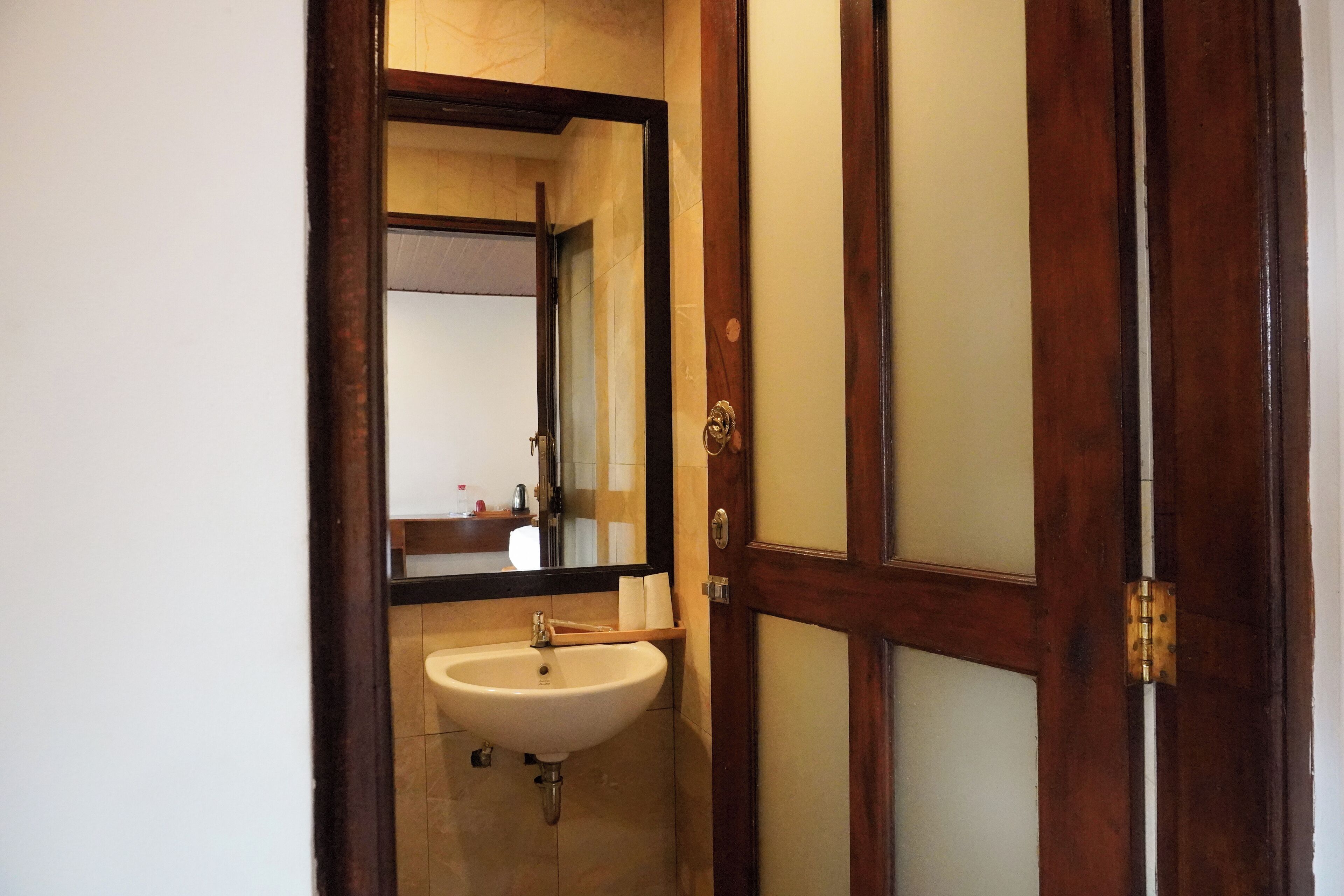 A bathroom with a wooden door, a white sink, and a mirror.
