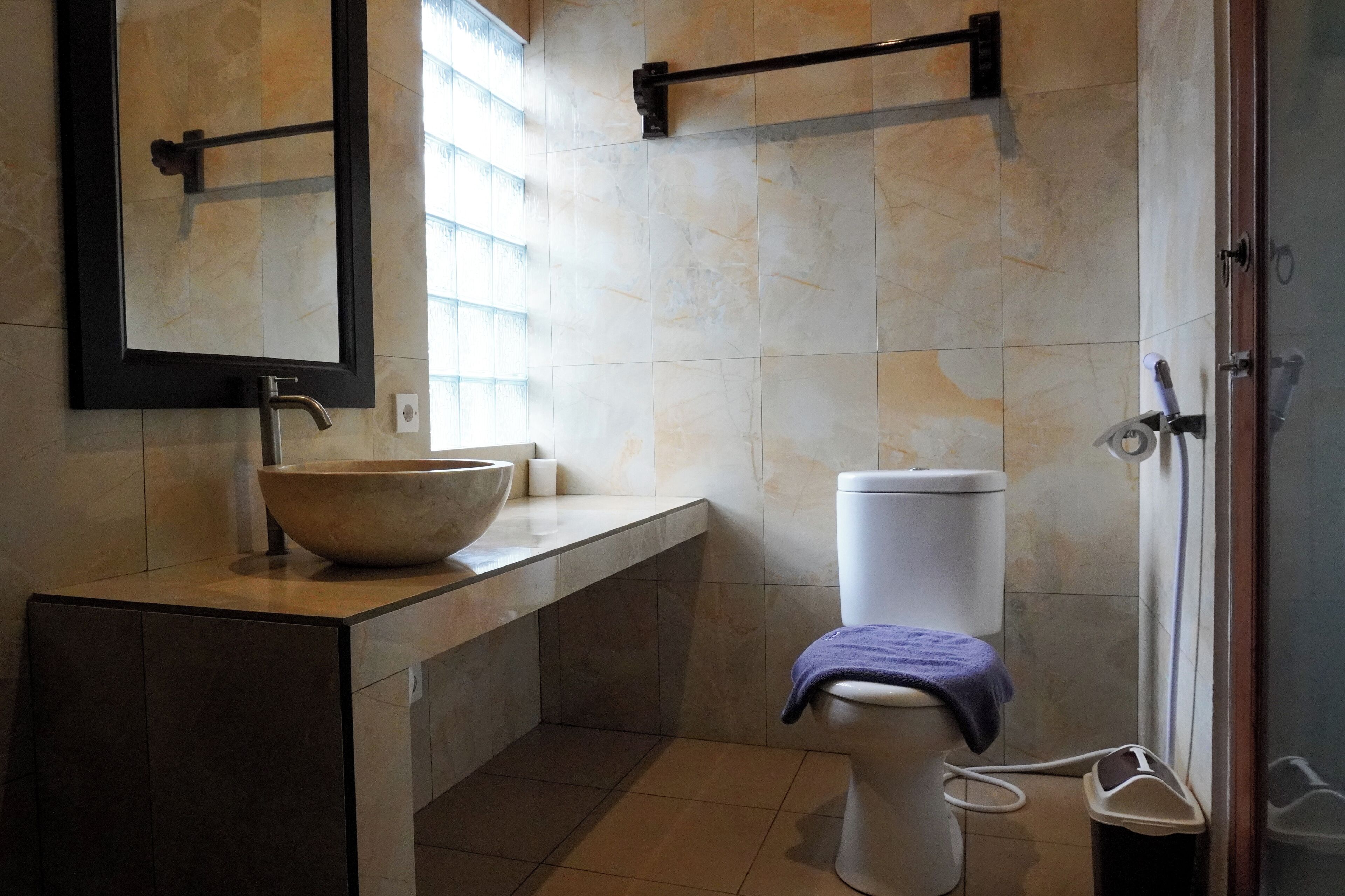 Un baño con un lavamanos grande, un inodoro y un espejo.