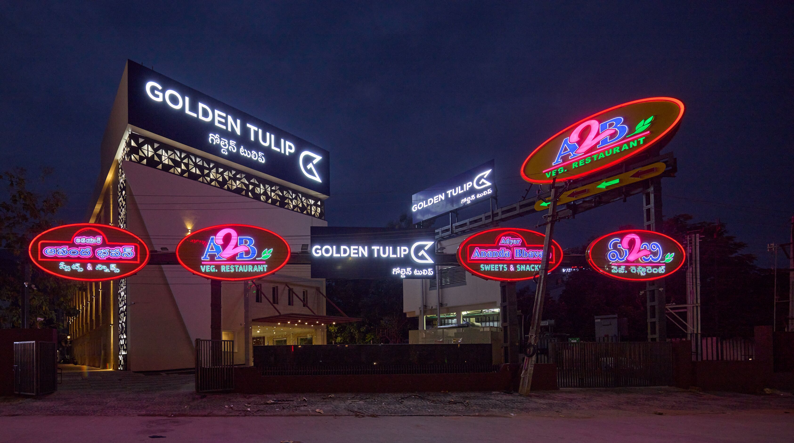 Un bâtiment orné de plusieurs enseignes, dont « GOLDEN TULIP » et « A2B VEG. RESTAURANT ».