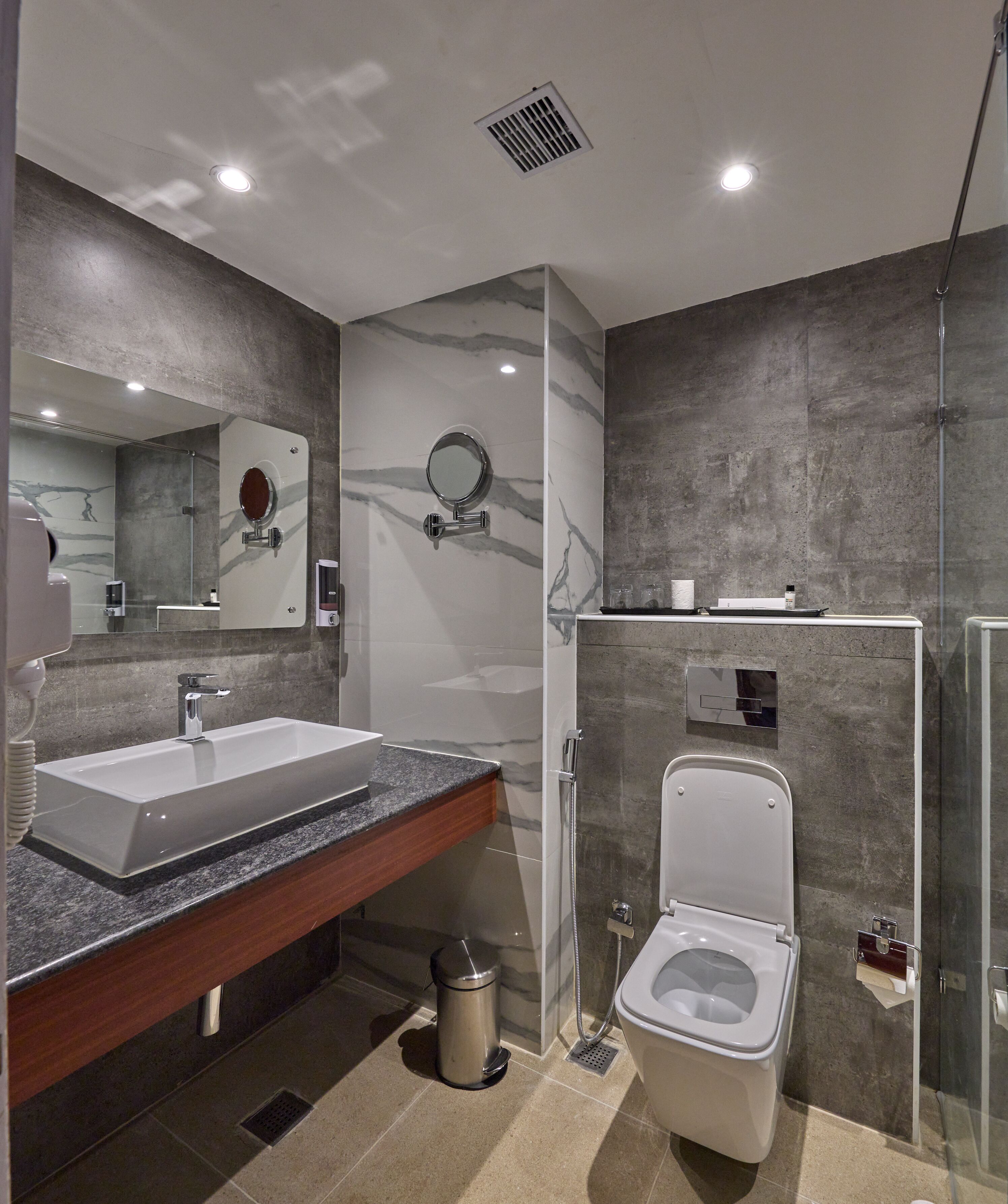 A modern bathroom with a large sink, mirror, and a glass-enclosed shower area.