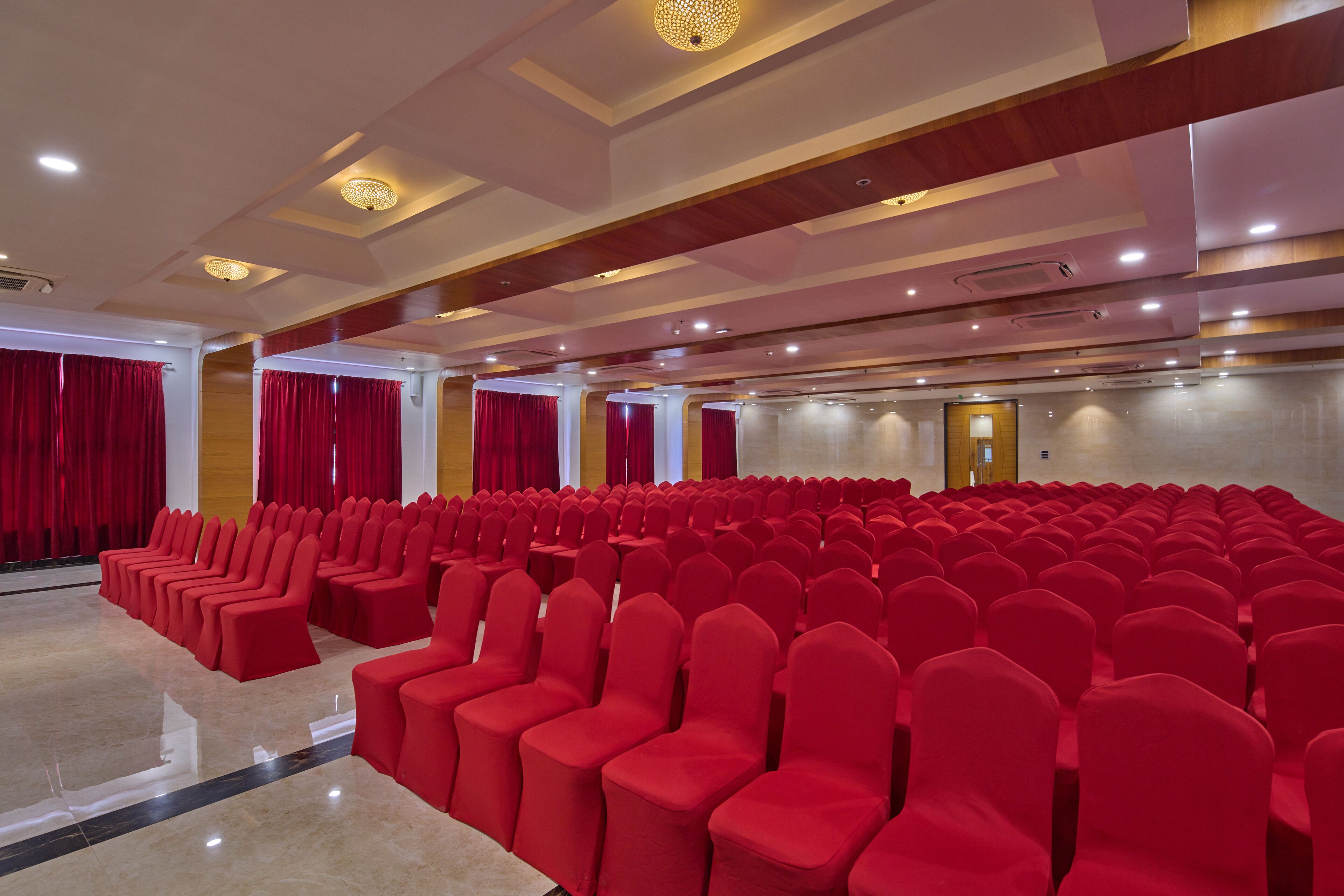 Un salón amplio con filas de sillas rojas, piso pulido y un diseño moderno del techo.