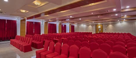 Un salón amplio con filas de sillas rojas, piso pulido y un diseño moderno del techo.
