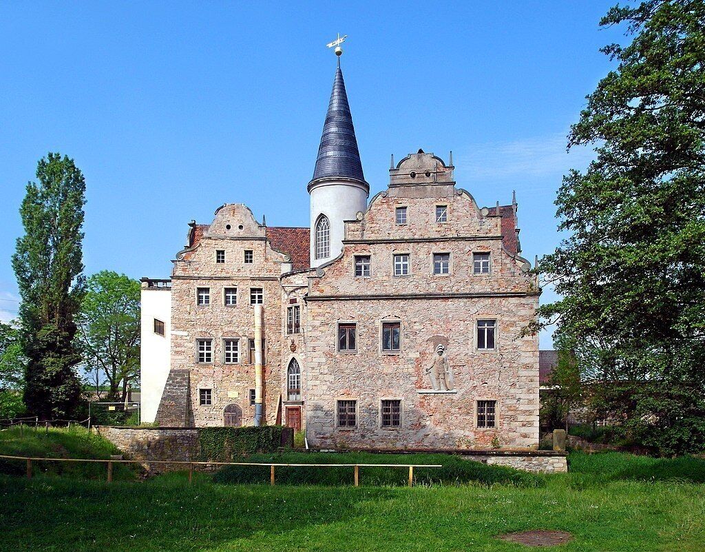Ein historisches Steinhaus mit einem markanten Turm und einer Statue an der Fassade.