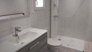 A modern bathroom with a white sink, vanity, and toilet.