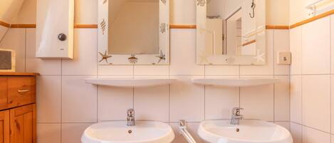 A bathroom with two sinks, a mirror, and a towel rack.