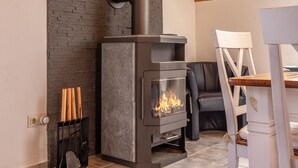 Een moderne haard met een glazen voorpaneel, een bakstenen muur erachter en een houten plafond.