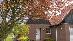 Een bakstenen huis met een witte deur en een kleine voortuin.