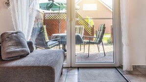 Een kamer met een schuifdeur die uitkomt op een terras met stoelen en een tafel.