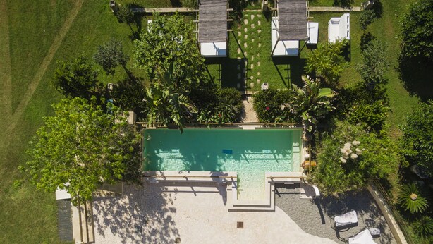 Eine Luftaufnahme einer Anlage mit Swimmingpool, Liegestühlen und einem gepflegten Rasen.