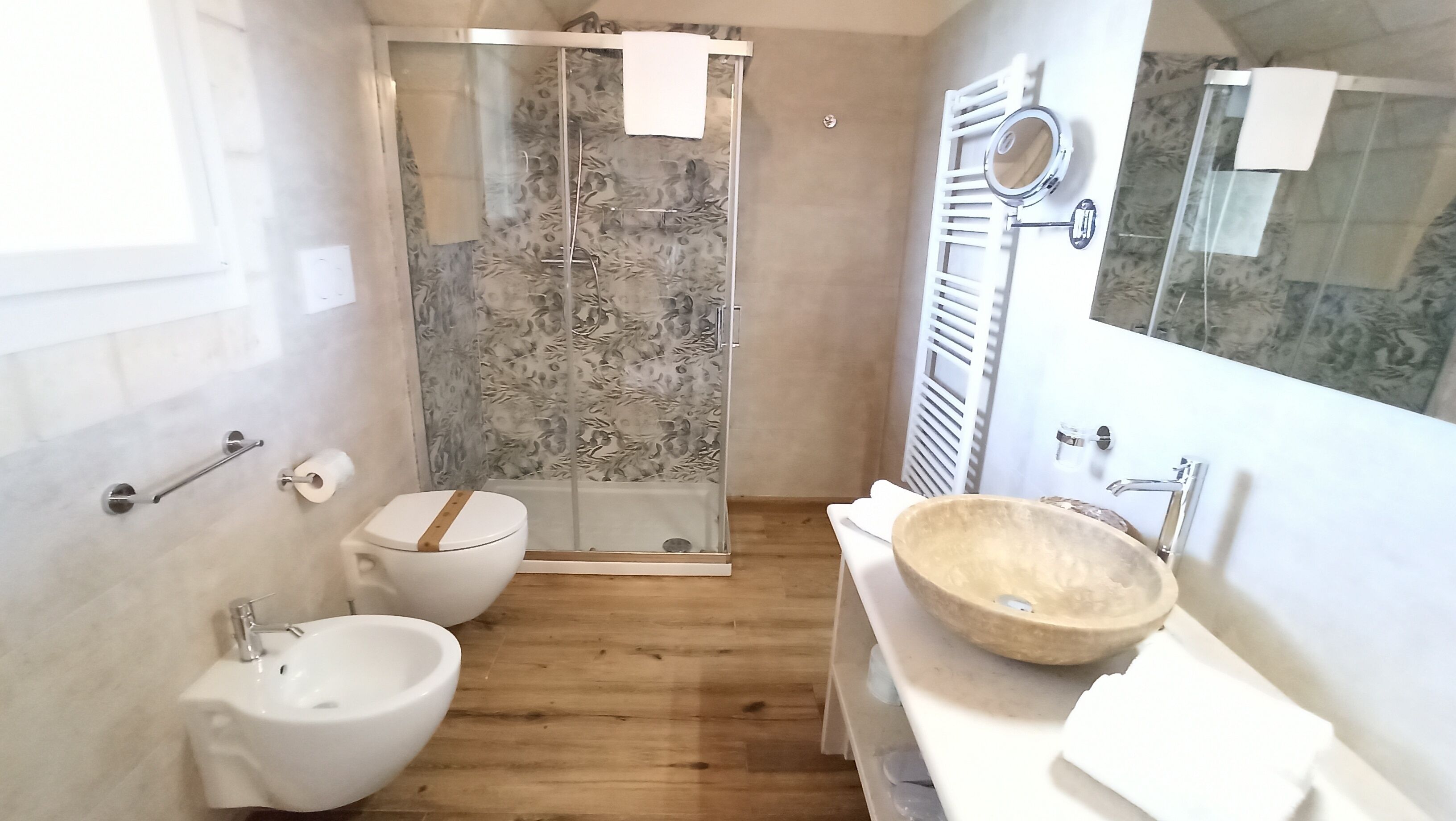 A modern bathroom with a shower, toilet, bidet, and a large basin.