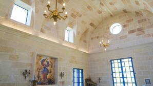 Ein Kircheninneres mit Steinwänden, einem großen Buntglasfenster und einer Chandelüster.