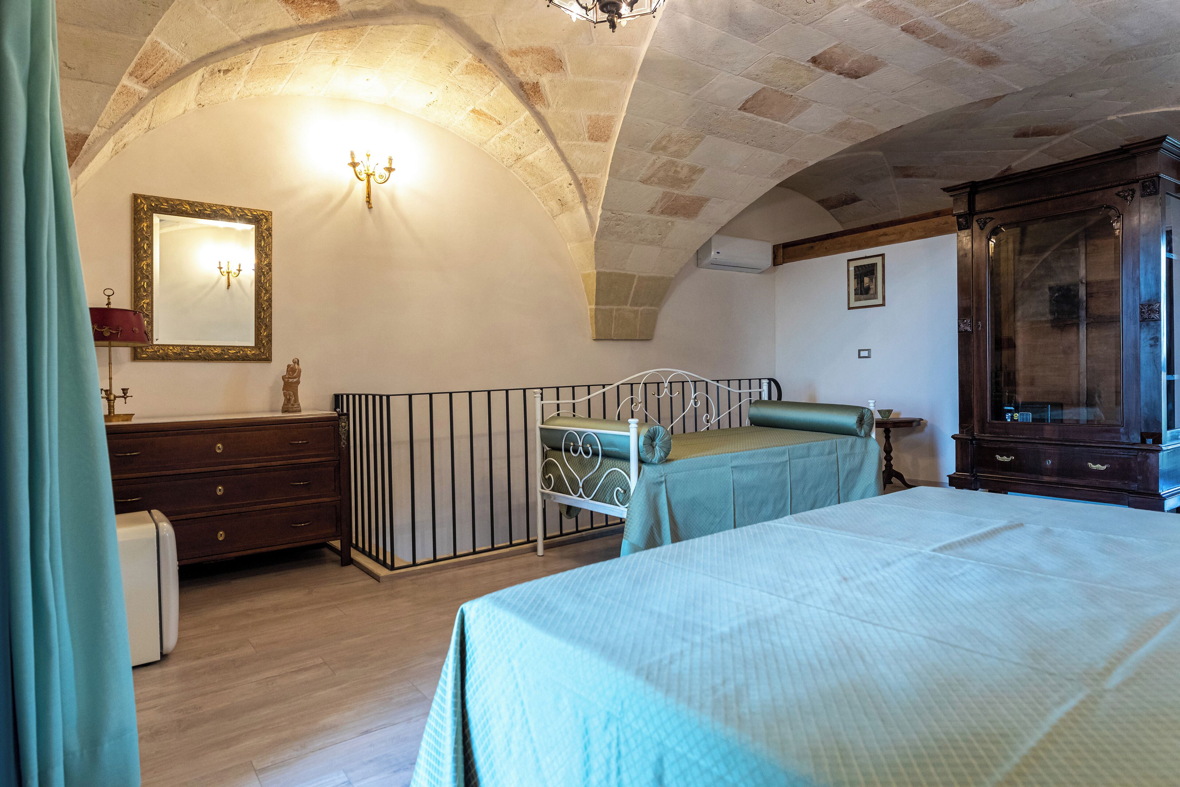 Une chambre à coucher avec un lit, une commode, un miroir et un lustre.