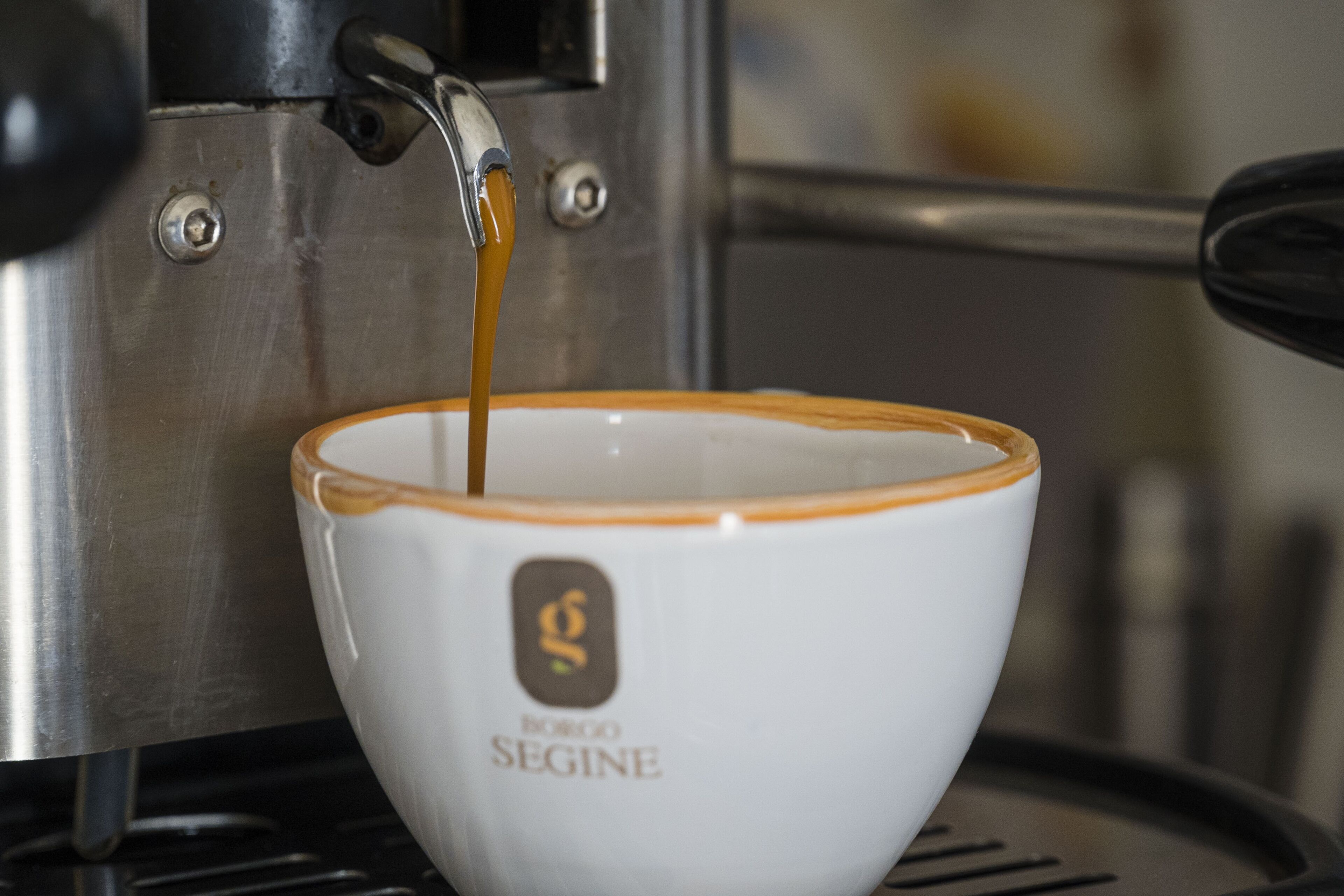 Una taza de café con un logotipo sobre una superficie metálica.