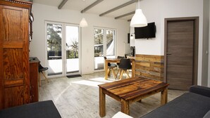 Un espacio habitable amplio con una mesa de comedor de madera, un sofá y un televisor montado en la pared.