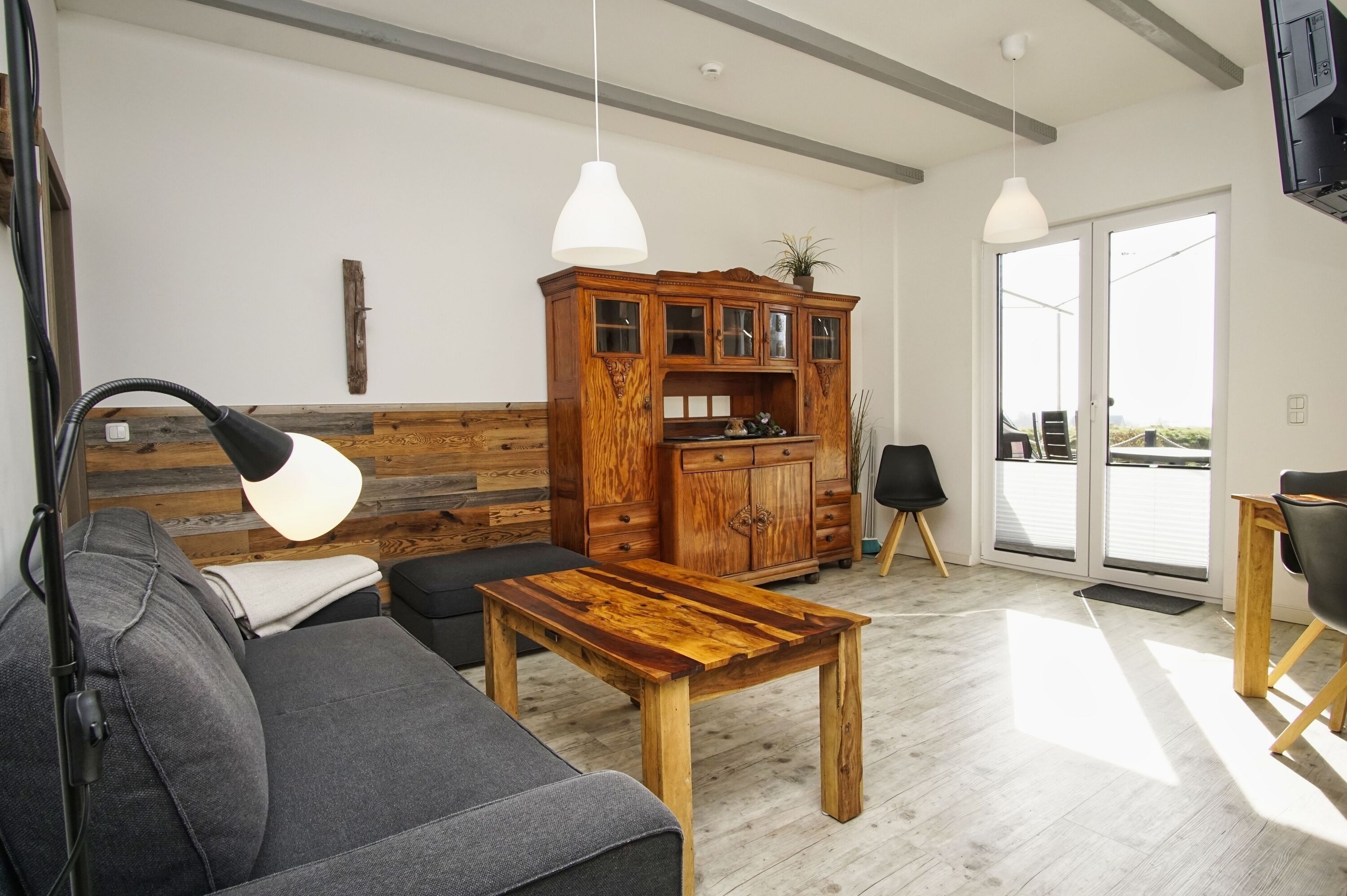 A modern living room with a wooden coffee table, grey sofa, and a wooden cabinet with glass doors.