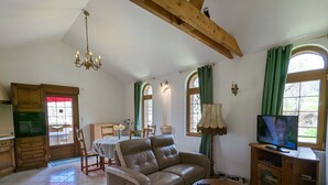 A living room with a leather sofa, a coffee table, a television, and a dining area with a table and chairs. - Converted chapel into independent cottage with terrace and fireplace (Saulxures-sur-Moselotte)