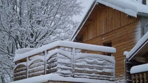 A wooden cabin with a snow-covered balcony and a brick foundation. - Converted chapel into independent cottage with terrace and fireplace (Saulxures-sur-Moselotte)
