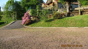 A house with a sloped roof, a balcony, and a garden with pink flowers. - Converted chapel into independent cottage with terrace and fireplace (Saulxures-sur-Moselotte)