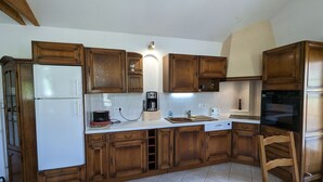 A compact kitchen with wooden cabinets, a white countertop, a built-in oven, and a coffee maker. - Converted chapel into independent cottage with terrace and fireplace (Saulxures-sur-Moselotte)
