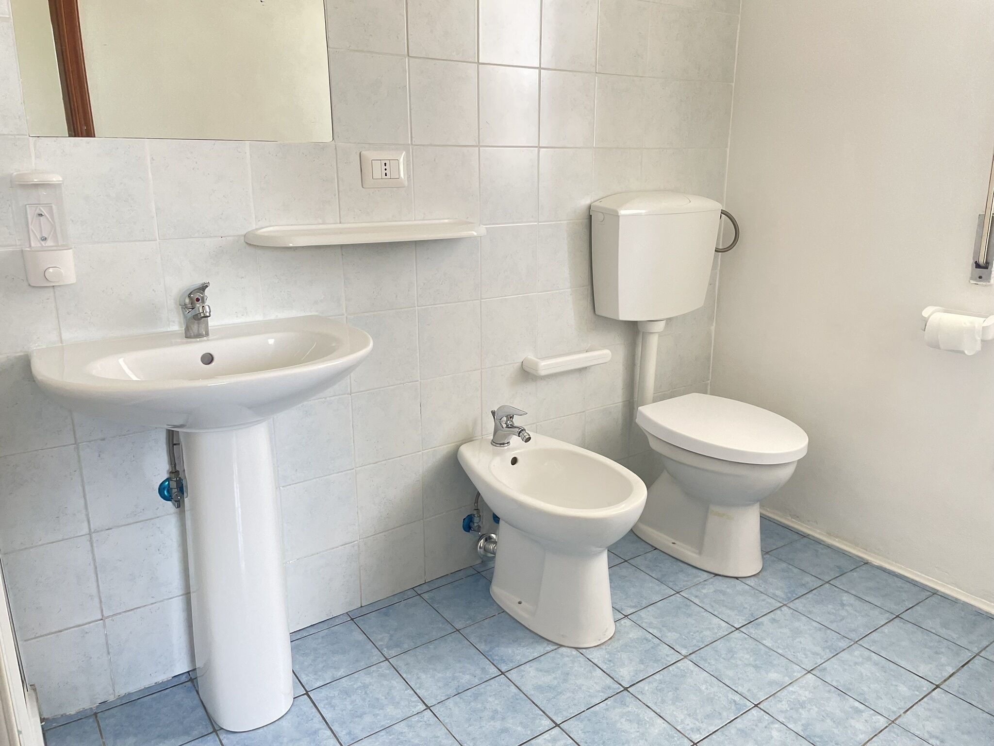 A bathroom with a pedestal sink, a bidet, and a toilet.