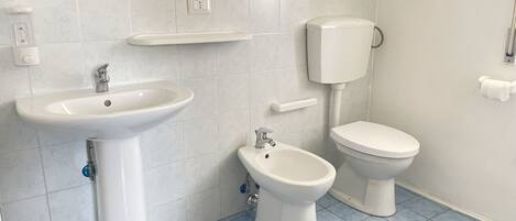 A bathroom with a pedestal sink, a bidet, and a toilet.