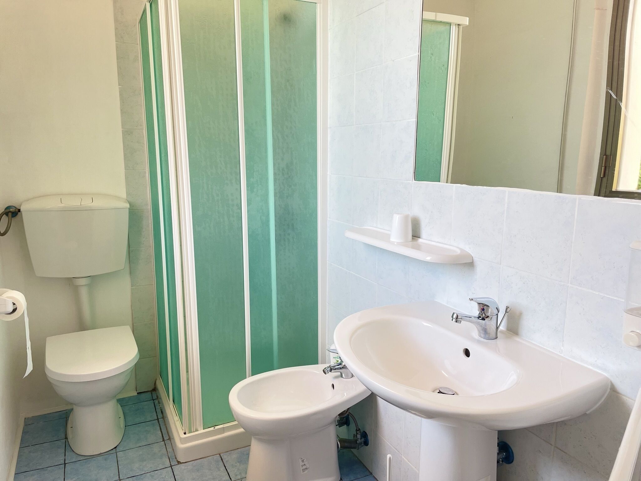Un bagno con WC, bidet, lavandino e cabina doccia.
