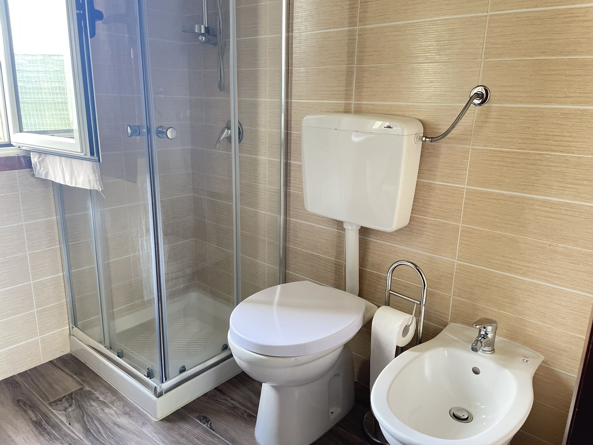 Un bagno con doccia vetrata, un water e un lavandino.
