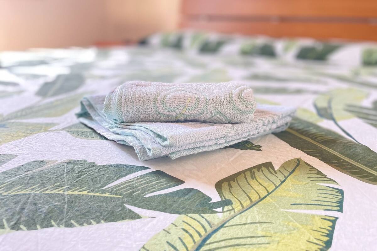A bed with a floral-patterned bedspread and a folded towel on it.