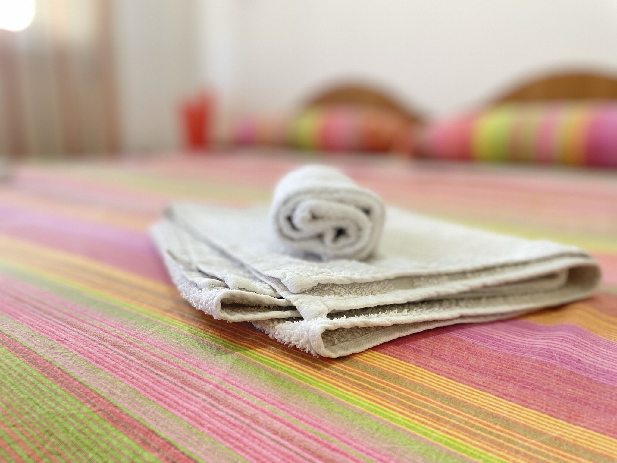 A neatly folded towel on a striped bedspread in a hotel room.