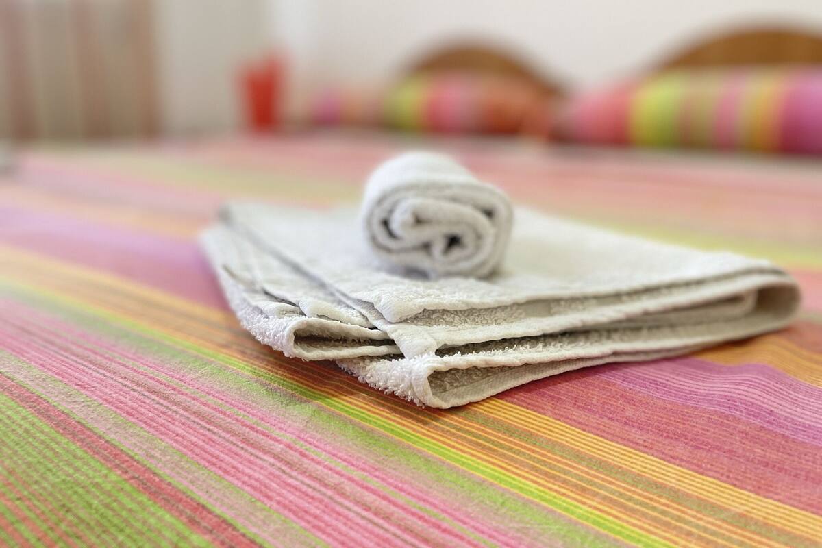 A neatly folded towel on a striped bedspread in a hotel room.
