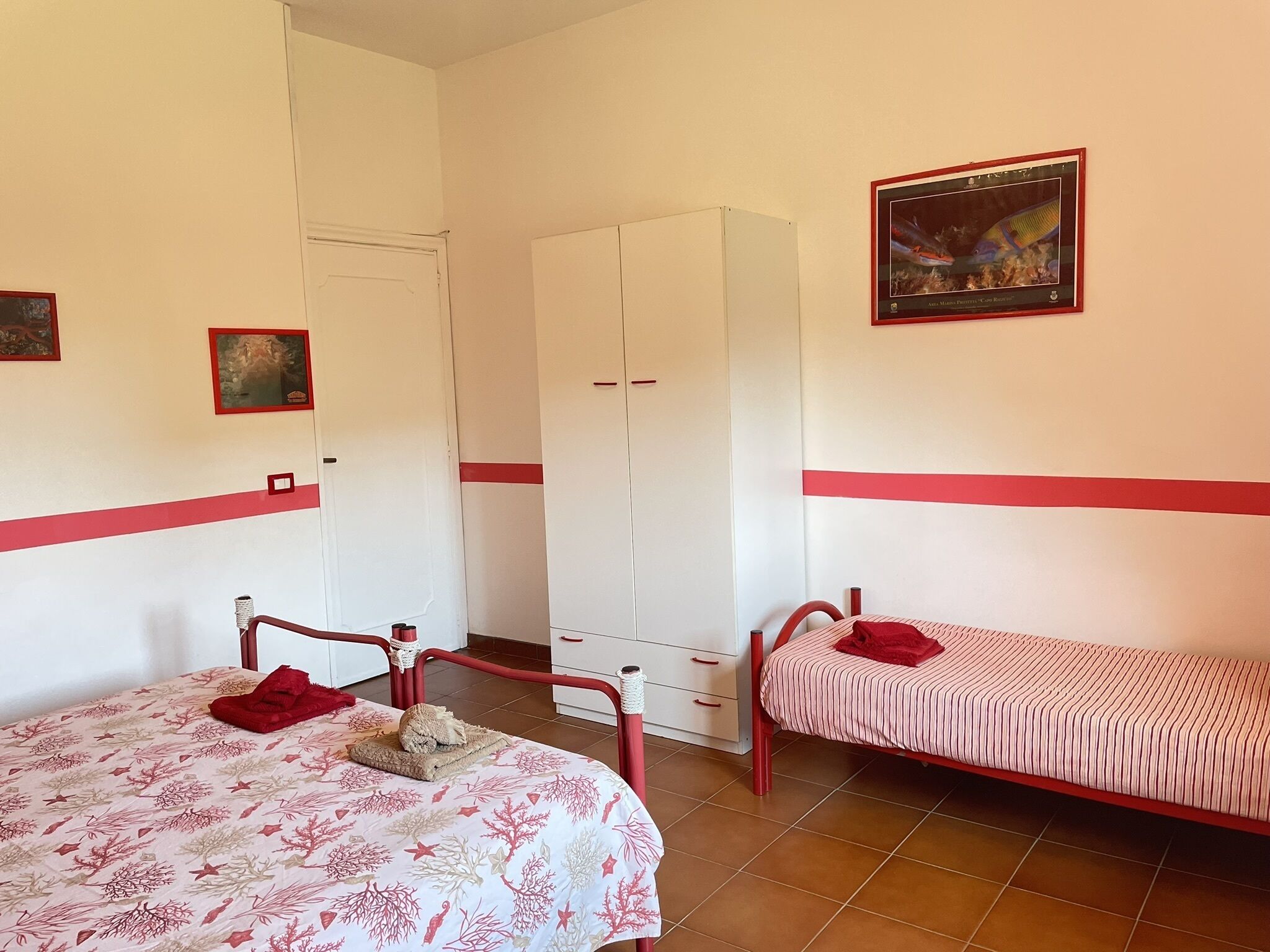 A room with two beds, a wardrobe, and a framed picture on the wall.